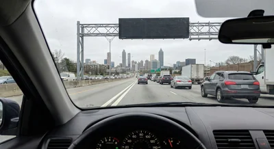 A driver's perspective of a wide, multi-lane highway in Atlanta, showing the flow of traffic on a sunny day.