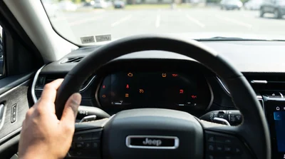 Driver in Pennsylvania checks glowing dashboard warning lights inside a rental car before departure.