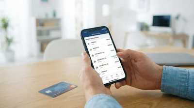 Person viewing a car rental refund transaction on a smartphone banking app screen indoors.