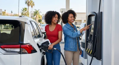 Couple refueling a white Toyota Rav4 at a sunny gas station near Los Angeles for car rental return.