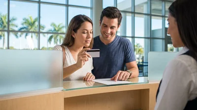 Close up of a person holding a credit card at a car hire counter in Miami
