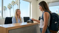 Close up of a person inserting a credit card into a terminal at a car rental desk in California