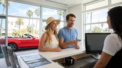 Person handing a credit card to an agent at a car rental desk in California