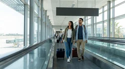 Travelers with luggage walking inside Orlando Airport towards the car rental counters