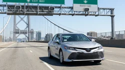 Driver in a white car rental approaching a toll plaza on a New York bridge