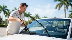 Driver checking the windshield wipers on a vehicle at a Florida car rental lot