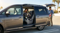 Parent buckling a toddler into a child seat inside a car rental parked on a sunny street in Texas