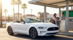 Close-up of a person handing a credit card to an agent at a California car hire desk