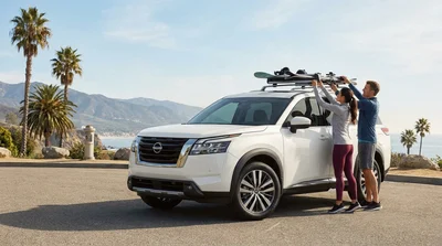 White SUV car hire with a ski rack driving along a snowy mountain road in California