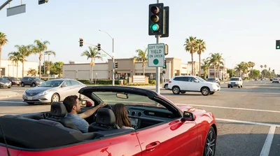 Driver in a car rental waiting to turn left at a green traffic light in California