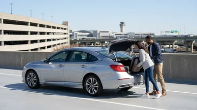 Rows of vehicles parked at an outdoor car rental lot near a New York airport terminal