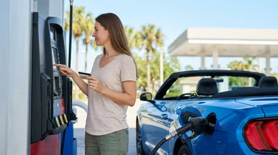 Person paying with a credit card at a gas pump next to a car rental in Florida