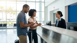 Traveler with luggage receiving keys at a car rental counter inside a Miami airport terminal