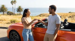 Two friends driving a white car rental along a scenic coastal highway in California