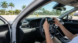 Person holding a smartphone to photograph the dashboard fuel gauge inside a car rental in Miami