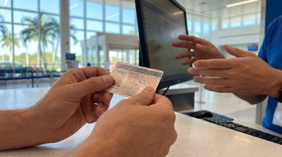 Close-up of a person holding a cracked driving licence at a Florida car rental desk