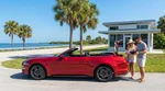 White car hire driving along a sunny coastal highway lined with palm trees in Florida