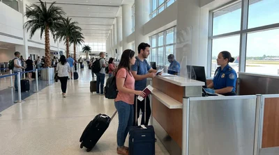 Travelers with suitcases waiting at a car rental counter inside Miami Airport