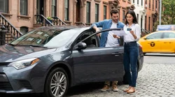 Two people exchanging keys for a car rental on a busy New York street