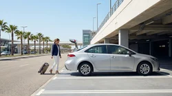 Traveler with luggage approaching a car rental desk at a Los Angeles airport terminal