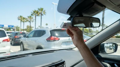 White car rental passing under a FasTrak toll plaza sign on a sunny California highway