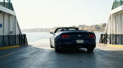 White car rental parked on the open deck of a passenger ferry crossing the water in sunny California