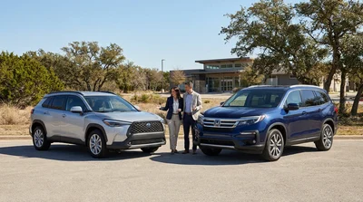 Two different sized SUVs parked side by side at a sunny Texas car hire lot
