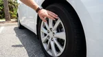 Close-up of a damaged wheel and hubcap on a silver car hire parked under palm trees in Florida