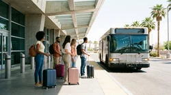 Travelers with rolling luggage boarding a car rental shuttle bus outside Terminal 1 in Las Vegas