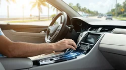 Close up of a hand on an automatic gear shift inside a car rental on a sunny Florida road