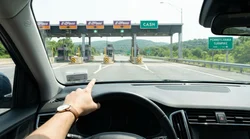A modern car rental passing through an E-ZPass toll plaza on a Pennsylvania highway