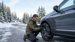 A car rental driving along a snowy pine-lined road in the mountains of California
