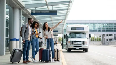 Travelers with luggage waiting for a car rental shuttle bus outside Newark Terminal B in New York