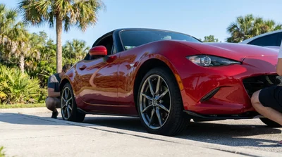 Close up of the front wheel and underbody of a car rental parked next to a kerb on a sunny Florida street