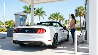 Person pumping gas into a car rental at a sunny Florida gas station