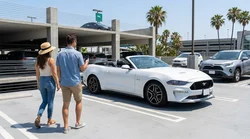 Traveler with luggage walking through a car rental pick-up bay at LAX airport in Los Angeles