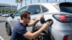 Close up of a person checking the fuel cap of a car rental in a sunny California parking lot