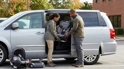 A securely fastened child seat in the back of a car rental parked on a scenic Pennsylvania road