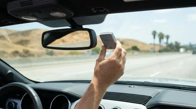 White car rental driving through a FasTrak toll lane on a sunny California highway