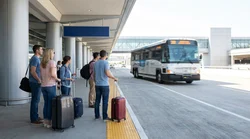 White shuttle bus picking up passengers with luggage at an airport terminal for car rental in New York