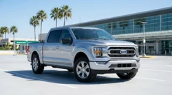 A white SUV car rental driving on a straight desert highway in Texas under a clear blue sky