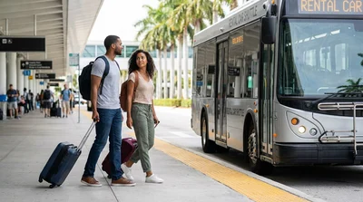 Passengers with luggage boarding a car rental shuttle bus outside a sunny Miami airport terminal