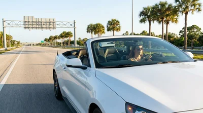 Driver in a car rental passing an express lane toll gantry on a Florida highway