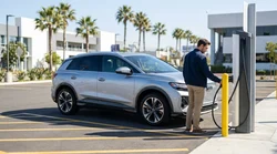 White electric car rental plugged into a charging station on a sunny Los Angeles street with palm trees