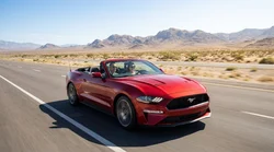A modern car rental driving on a scenic desert highway towards the Las Vegas skyline at sunset
