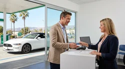 Close up of a customer handing a credit card to a clerk at a car rental desk in California