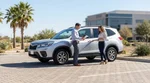 Two people exchanging keys inside a car rental parked on a sunny road in Texas