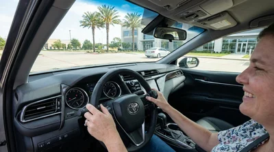 Close-up of hands operating adaptive driving controls inside a car rental on a sunny Texas highway