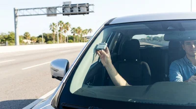 White car rental passing under a cashless toll gantry on a sunny highway in Orlando