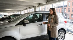 Person holding car keys next to a modern car rental vehicle parked on a New York street